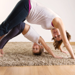 Young pregnant woman with little daughter doing yoga exercises