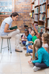 Cute pupils sitting on floor in library at the elementary school