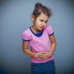 girl child abdominal pain on a gray background cross process